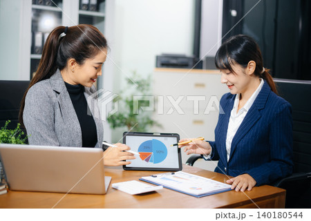 Two businesswoman discuss investment project working and planning strategy with tablet laptop computer in modern office. Two businesswoman discuss investment project working and planning strategy with tablet laptop computer in modern office. 140180544