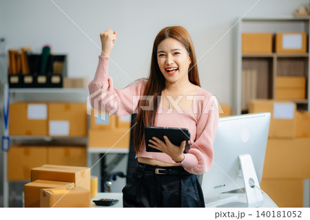 Asian woman prepares parcels and checks online orders on tablet and laptop for delivery online shopping Asian woman prepares parcels and checks online orders on tablet and laptop for delivery online shopping 140181052