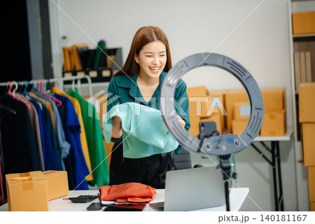 Young Asian women selling clothes on video streaming.Startup small business SME, using smartphone Young Asian women selling clothes on video streaming.Startup small business SME, using smartphone 140181167