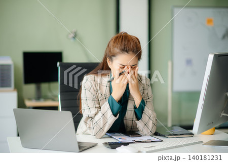 Asian woman feeling migraine head strain.Overworked businesswoman financier while working on laptop Asian woman feeling migraine head strain.Overworked businesswoman financier while working on laptop 140181231