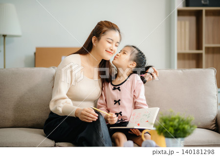 A caring mother and young daughter share a bonding moment doing homework at home. 140181298