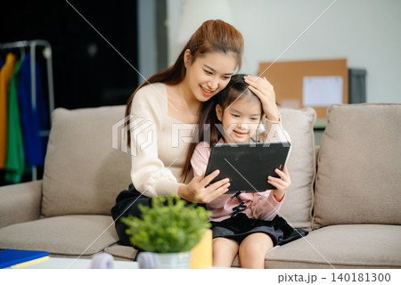 A caring mother and young daughter share a bonding moment doing homework at home. A caring mother and young daughter share a bonding moment doing homework at home. 140181300