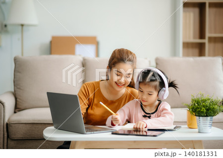 A caring mother and young daughter share a bonding moment doing homework at home. A caring mother and young daughter share a bonding moment doing homework at home. 140181331