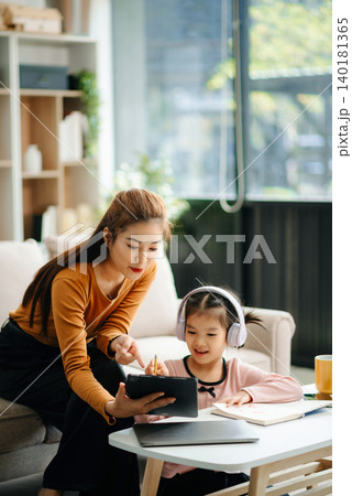 A caring mother and young daughter share a bonding moment doing homework at home. A caring mother and young daughter share a bonding moment doing homework at home. 140181365