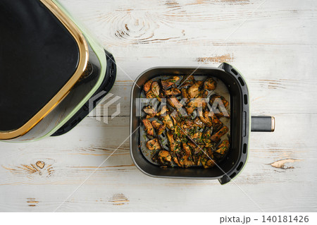 Oyster mushrooms cooked in an air fryer on a wooden table with a black lid nearby Oyster mushrooms cooked in an air fryer on a wooden table with a black lid nearby 140181426