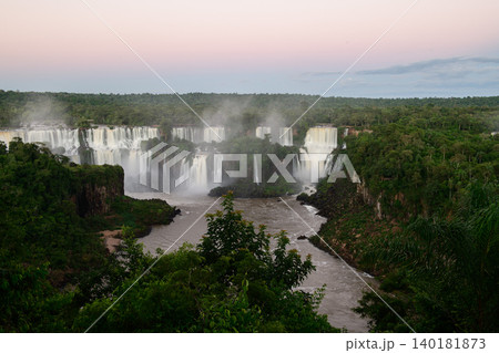 Majestic iguazu falls pouring into tranquil river surrounded by dense forest mist Majestic iguazu falls pouring into tranquil river surrounded by dense forest mist 140181873