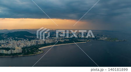 Dramatic aerial view of Rio de Janeiro cityscape under dark cloudy sky at dawn. tranquil coastline along sea Dramatic aerial view of Rio de Janeiro cityscape under dark cloudy sky at dawn. tranquil coastline along sea 140181899