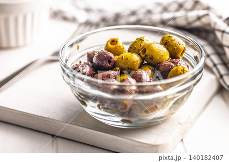 Marinated Mixed Olives in Glass Bowl on Wooden Board With Herbs and Olive Oil Marinated Mixed Olives in Glass Bowl on Wooden Board With Herbs and Olive Oil 140182407