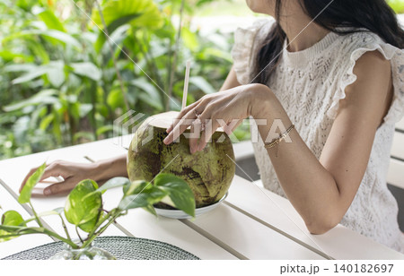 woman drinking fresh coconit in tropical outdoors garden cafe in bali indonesia woman drinking fresh coconit in tropical outdoors garden cafe in bali indonesia 140182697