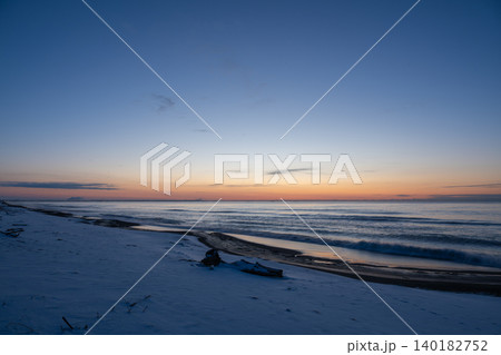朝日前の静かな恋問海岸。雪の浜辺と穏やかな波が広がる北海道白糠町のブルーアワーの風景。 朝日前の静かな恋問海岸。雪の浜辺と穏やかな波が広がる北海道白糠町のブルーアワーの風景。 140182752