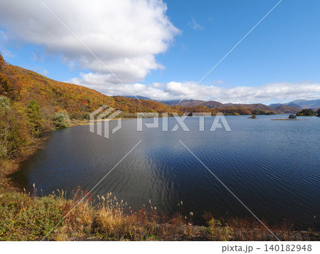 秋の裏磐梯、秋元湖。紅葉した山肌に青い湖面と空が印象的で綺麗だ。 秋の裏磐梯、秋元湖。紅葉した山肌に青い湖面と空が印象的で綺麗だ。 140182948