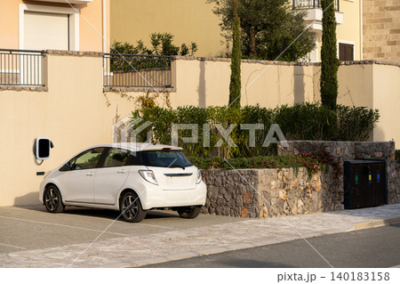 Small electric car next to charging station on a city street 140183158