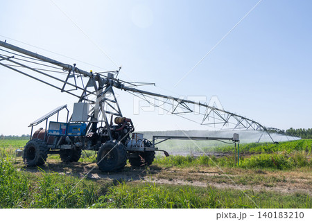 Autonomous machine is moving watering pivot along irrigation canal. Autonomous machine is moving watering pivot along irrigation canal. 140183210