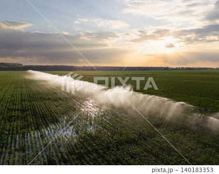 Agricultural watering pivot irrigation system on a corn field at sunset. Agricultural watering pivot irrigation system on a corn field at sunset. 140183353