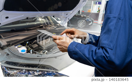 Serviceman with digital tablet on the background of the car in the car service. Serviceman with digital tablet on the background of the car in the car service. 140183645