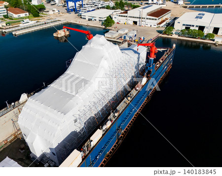 Aerial view of a luxury yacht refit, repair, service and maintenance in a floating dock at a marina. Aerial view of a luxury yacht refit, repair, service and maintenance in a floating dock at a marina. 140183845