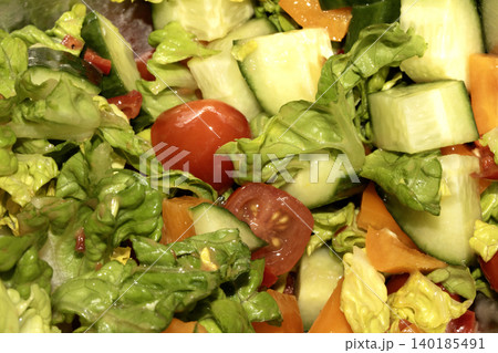 Close up of a mixed summer salad with lettuce cucumber and tomatoes Close up of a mixed summer salad with lettuce cucumber and tomatoes 140185491