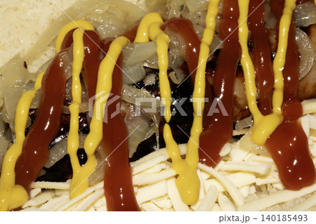 Close up of a hot dog with ketchup and mustard squirted on top dressing Close up of a hot dog with ketchup and mustard squirted on top dressing 140185493