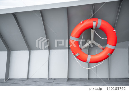 Orange lifebuoy or life preserver ring hanging on side wall of steel boat Orange lifebuoy or life preserver ring hanging on side wall of steel boat 140185762