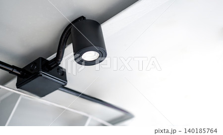 Modern black cylindrical downlight or cylinder LED spotlight hanging on the ceiling 140185764