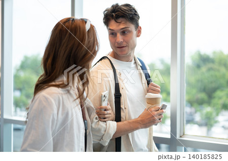 Asian woman girlfriend linking arms talking to white man boyfriend while walking in airport building Asian woman girlfriend linking arms talking to white man boyfriend while walking in airport building 140185825