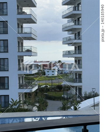 Modern beachfront resort architecture with balconies and pool under partly cloudy skies 140185940