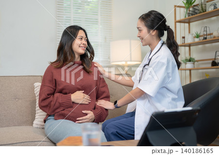 Asian woman doctor comforting talking to young pregnant patient sitting on sofa in hospital clinic. Asian woman doctor comforting talking to young pregnant patient sitting on sofa in hospital clinic. 140186165