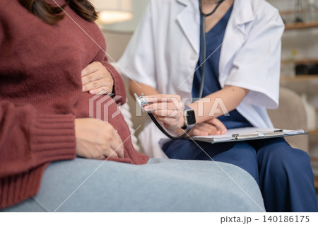 Close up of doctor holding stethoscope checking up pregnant patient's baby belly in hospital clinic. 140186175
