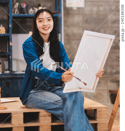 Female artist wears black hat posing near picture indoor the studio 140186506