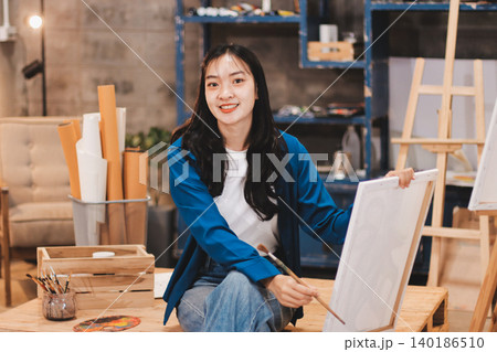 Female artist wears black hat posing near picture indoor the studio 140186510