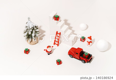 Christmas Miniature Flatlay with Santa Figurine Snowy Tree Toy Truck and Gift Boxes White Background Christmas Miniature Flatlay with Santa Figurine Snowy Tree Toy Truck and Gift Boxes White Background 140186924