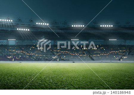 A low-angle shot of a lush green grass field in a large sports stadium at night, with bright floodlights illuminating the arena and blurred stands in the background A low-angle shot of a lush green grass field in a large sports stadium at night, with bright floodlights illuminating the arena and blurred stands in the background 140186948