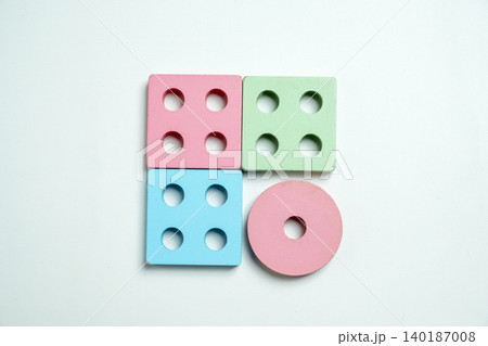 Top-down view of colorful wooden geometric toy blocks on a white background, featuring squares and a circle for educational sorting and childhood development 140187008