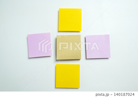 Five blank colorful adhesive notes in a plus sign arrangement on a white surface, ideal for office planning, project management, and creative brainstorming sessions 140187024
