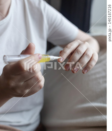 Woman applying nourishing oil on cuticles using a convenient nail cuticle oil pen with brush. Professional home manicure, hand skin health care and treatment. Woman applying nourishing oil on cuticles using a convenient nail cuticle oil pen with brush. Professional home manicure, hand skin health care and treatment. 140187216