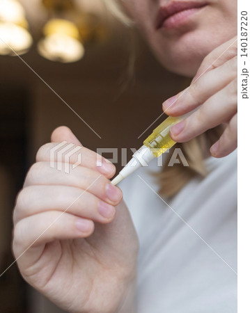 Woman applying nourishing oil on cuticles using a convenient nail cuticle oil pen with brush. Professional home manicure, hand skin health care and treatment. 140187220