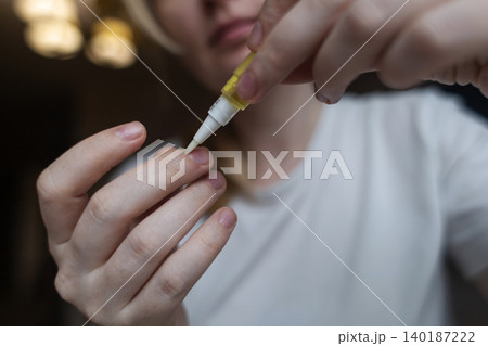 Woman applying nourishing oil on cuticles using a convenient nail cuticle oil pen with brush. Professional home manicure, hand skin health care and treatment. Woman applying nourishing oil on cuticles using a convenient nail cuticle oil pen with brush. Professional home manicure, hand skin health care and treatment. 140187222
