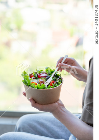 A woman holds a healthy vegetable salad in an eco-friendly takeaway bowl. A woman holds a healthy vegetable salad in an eco-friendly takeaway bowl. 140187438
