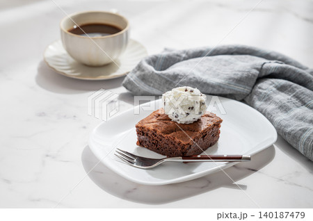 A piece of chocolate brownie with ice cream on a plate and a cup of espresso coffee A piece of chocolate brownie with ice cream on a plate and a cup of espresso coffee 140187479