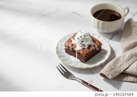 A piece of chocolate brownie with ice cream on a plate and a cup of espresso coffee A piece of chocolate brownie with ice cream on a plate and a cup of espresso coffee 140187484