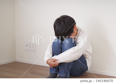 壁際で膝を抱えてうずくまる男の子 壁際で膝を抱えてうずくまる男の子 140190070