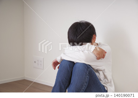壁際で膝を抱えてうずくまる男の子 壁際で膝を抱えてうずくまる男の子 140190071