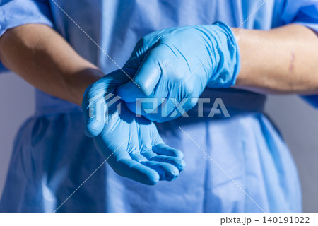 Healthcare professional putting on blue medical gloves on white background with copy space Healthcare professional putting on blue medical gloves on white background with copy space 140191022