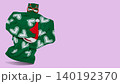 Funny invisible character concept with green knitted sweater holding Santa hat and wearing Christmas party glasses, levitating on purple background. 140192370