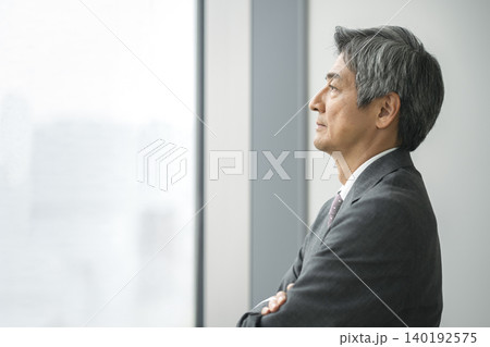 腕組みをして窓の外を見る60代のビジネスマン 横顔 腕組みをして窓の外を見る60代のビジネスマン 横顔 140192575