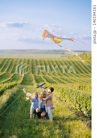 Mother and children flying kite and toy planes 140194161