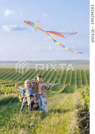 Mother and sons flying kite enjoying summer outdoors 140194163