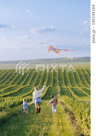 Mother and children flying kite in green field Mother and children flying kite in green field 140194164