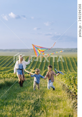 Mother and children flying kite and playing outdoors Mother and children flying kite and playing outdoors 140194168