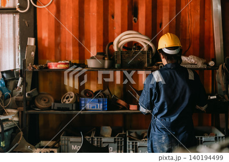 Staff worker man working in old metal part stock warehouse storage looking search for machine part. 140194499